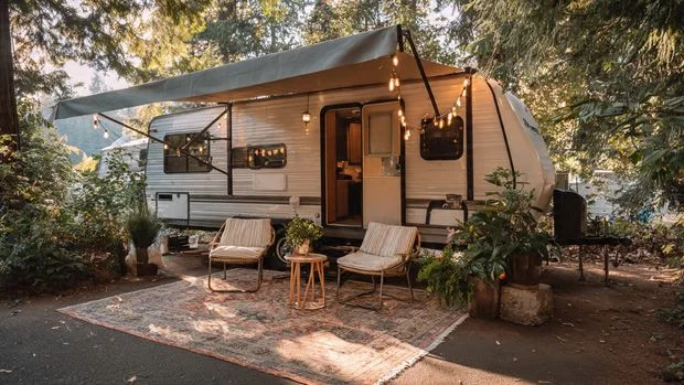 RV campsite setup with outdoor rug, chairs, and awning extended